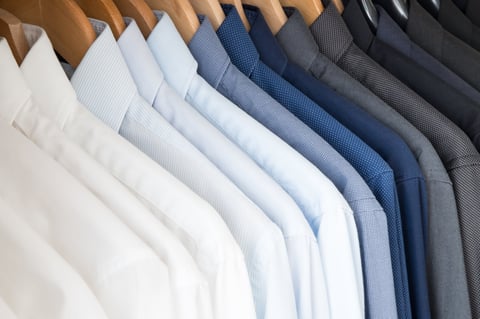 Shirts hanging in a closet ordered by colour Overlapping shirts creating a beautiful pattern